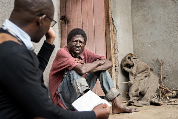 Saulos Metio speaks with Charles Marshal, at PIH Malawi, during a home visit as part of his ongoing treatment and nutritional support.