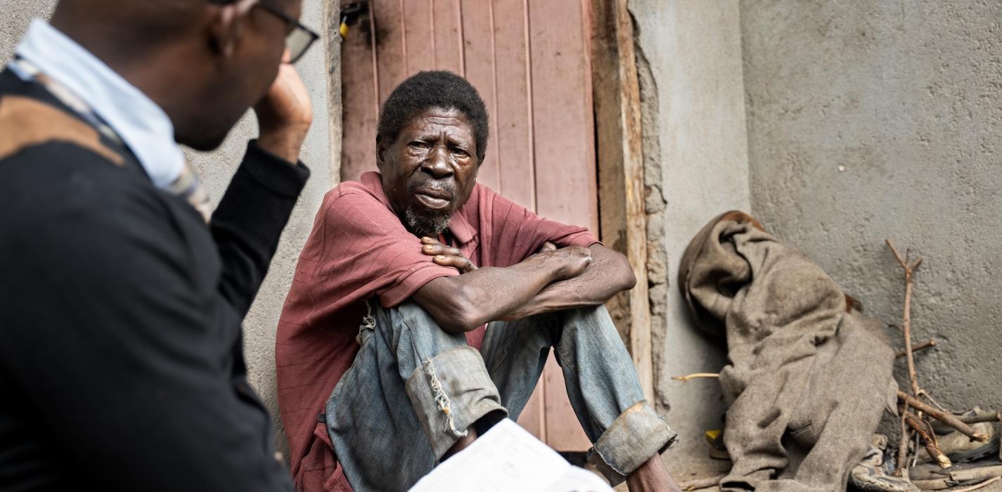 Saulos Metio speaks with Charles Marshal, at PIH Malawi, during a home visit as part of his ongoing treatment and nutritional support.